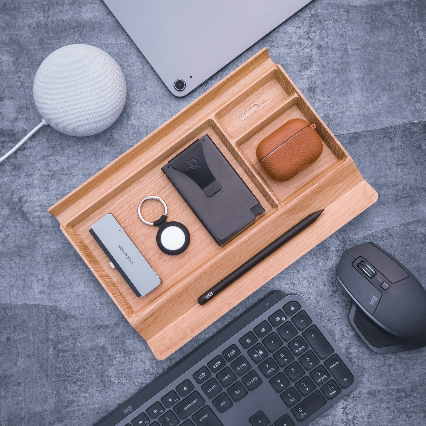 Moderni gadget tecnologici ordinatamente disposti in un organizer da scrivania in legno.