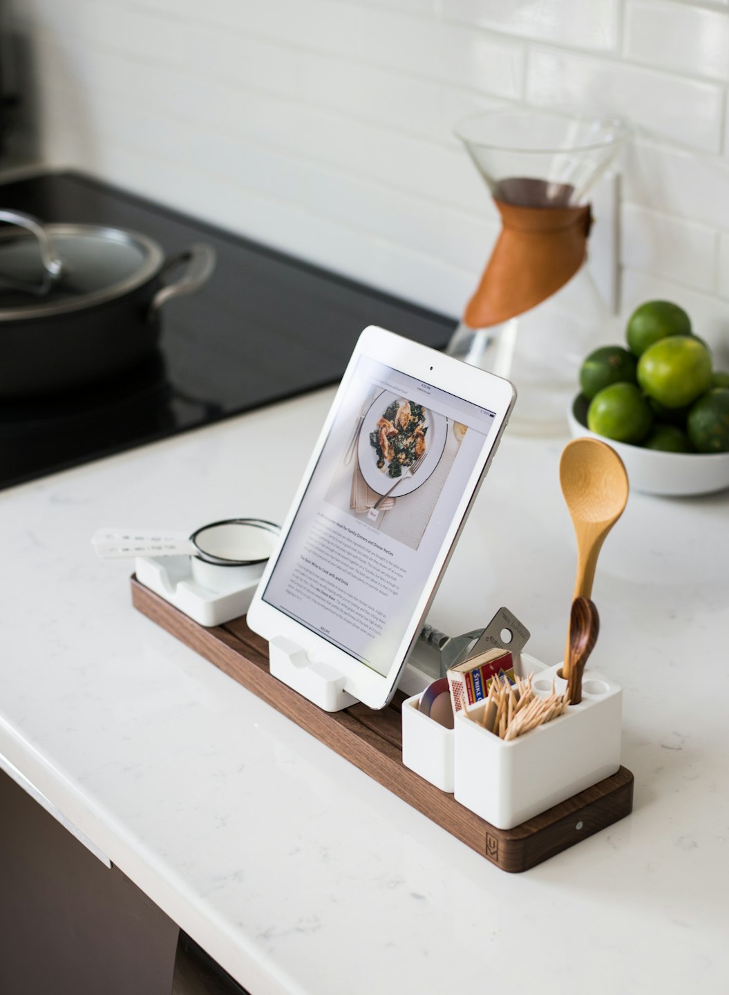 Piano di lavoro della cucina con ricetta su iPad, macchina da caffè e lime.
