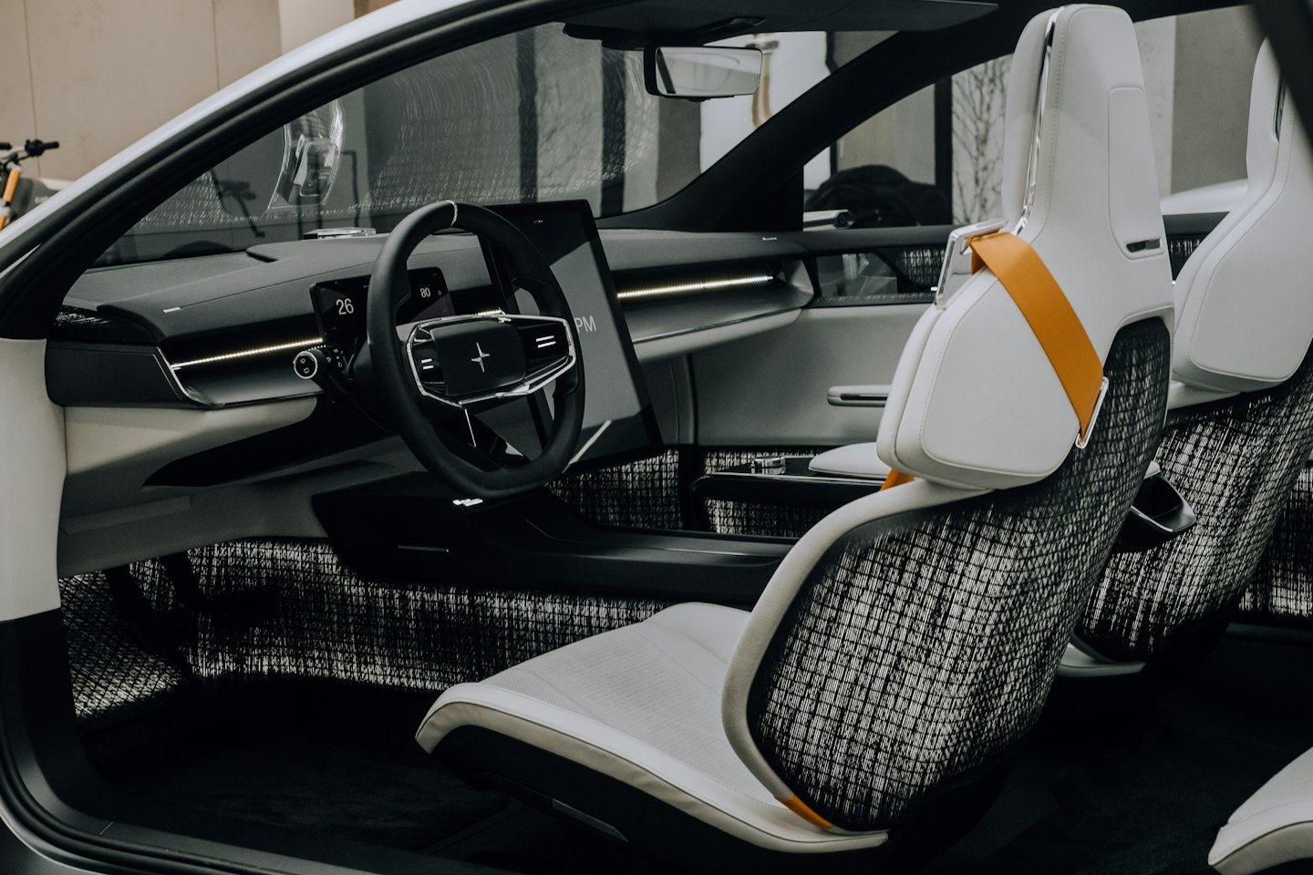 Cruscotto e volante di un'auto moderna con cintura di sicurezza arancione.